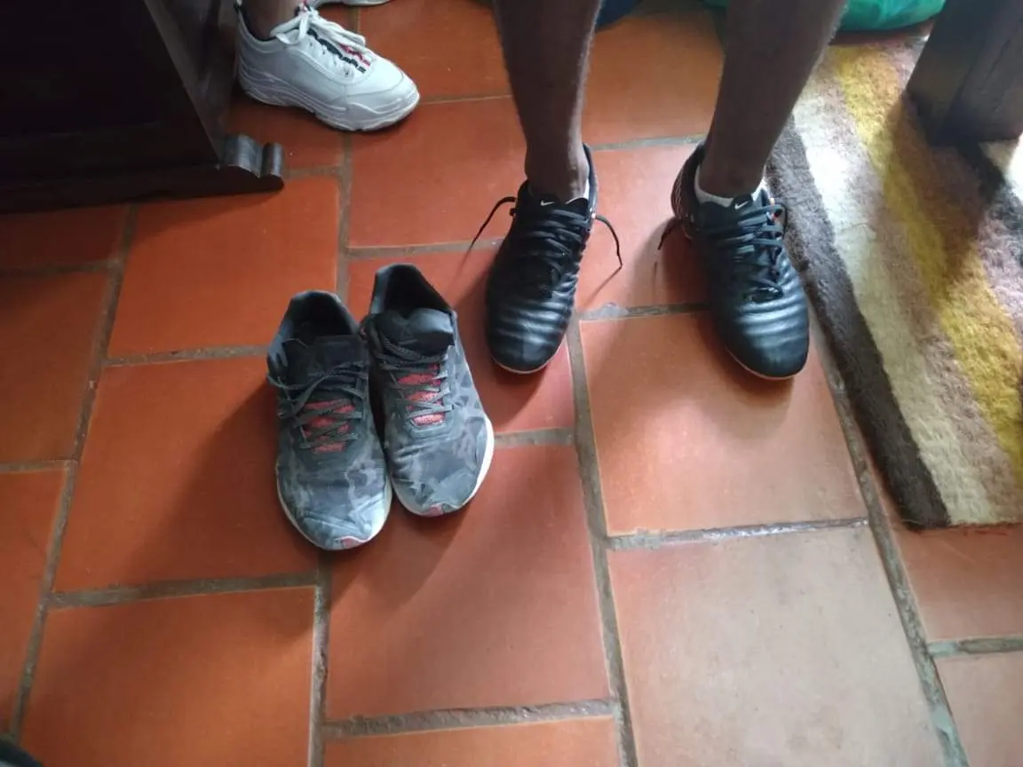 Person wearing new black sports shoes with worn-out shoes beside them.
